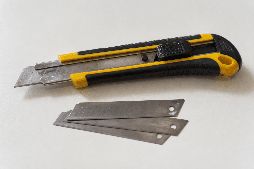 Cutter avec lames de rechange sur surface blanche