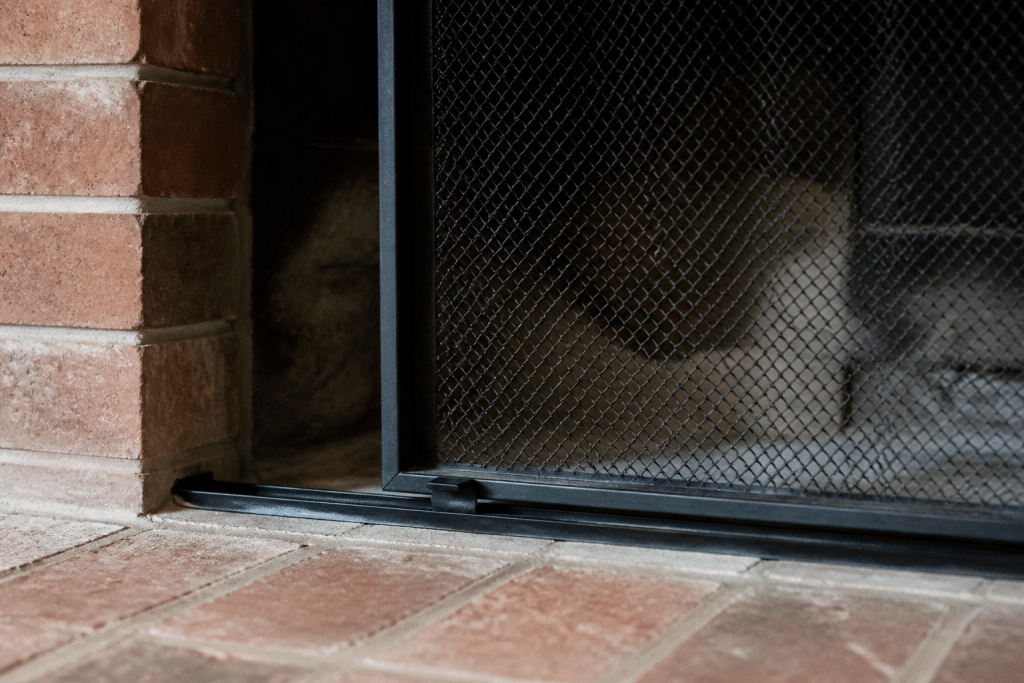 Grille metallique positionnee sur rails dans foyer brique