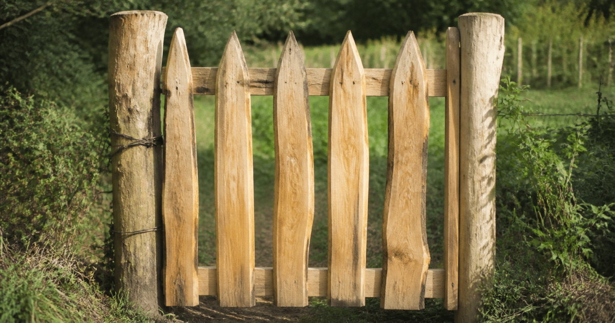 Portail rustique en bois brut debout entre deux poteaux verticaux