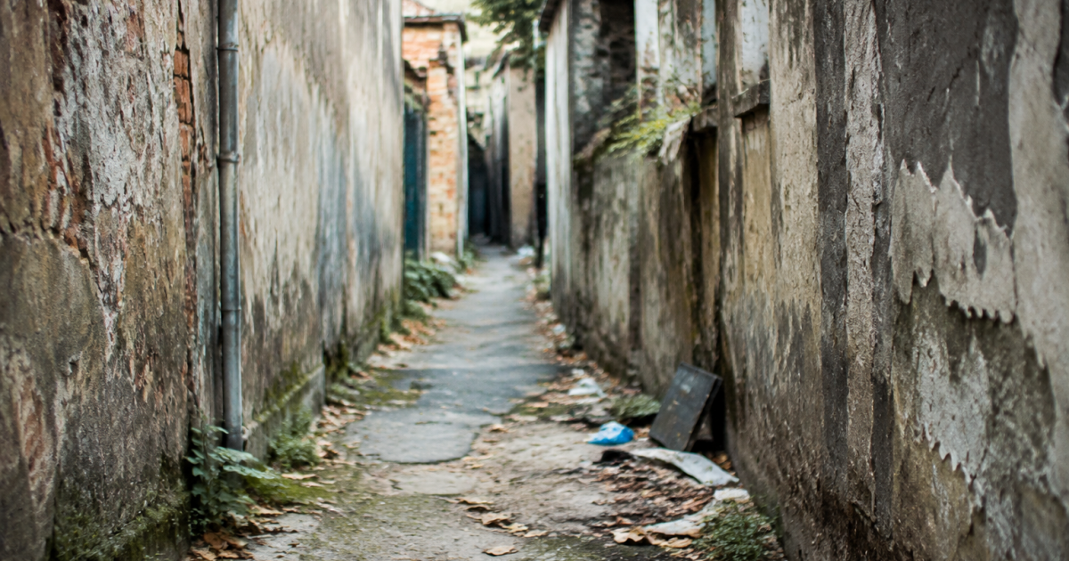 Ruelle abandonnee avec murs degrades et detritus au sol