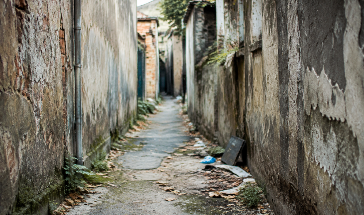 Ruelle abandonnee avec murs degrades et detritus au sol