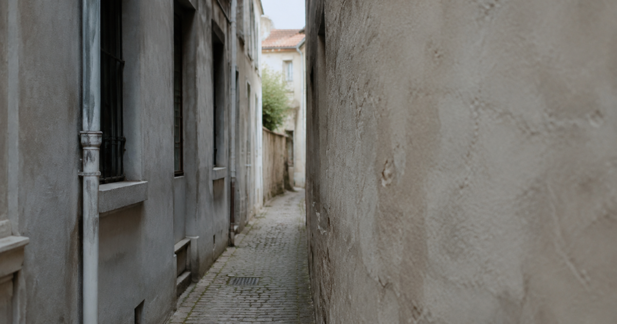Ruelle etroite entre facades grises et murs nus