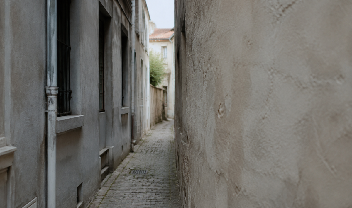 Ruelle etroite entre facades grises et murs nus