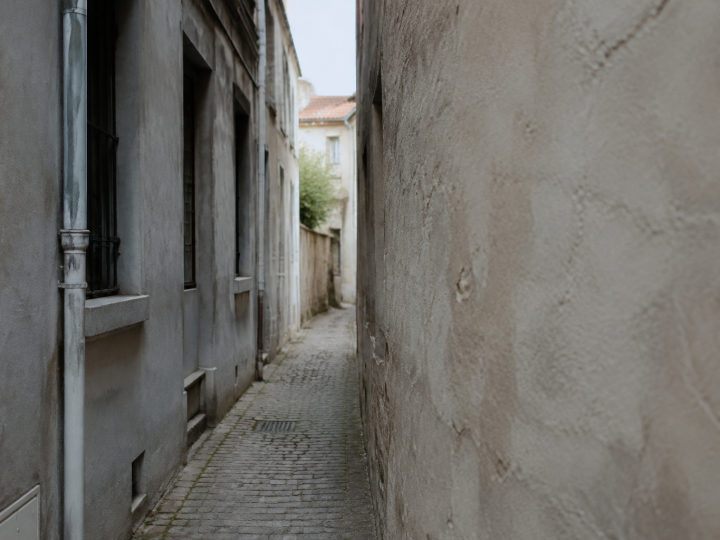 Ruelle etroite entre facades grises et murs nus