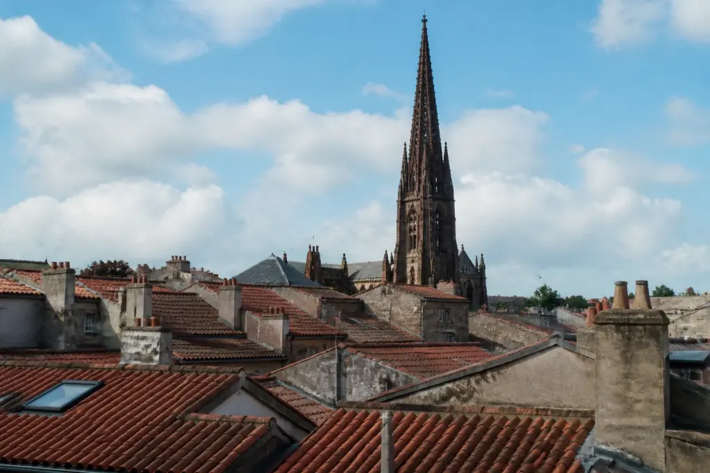 Toits rouges et clocher gothique sous un ciel bleu